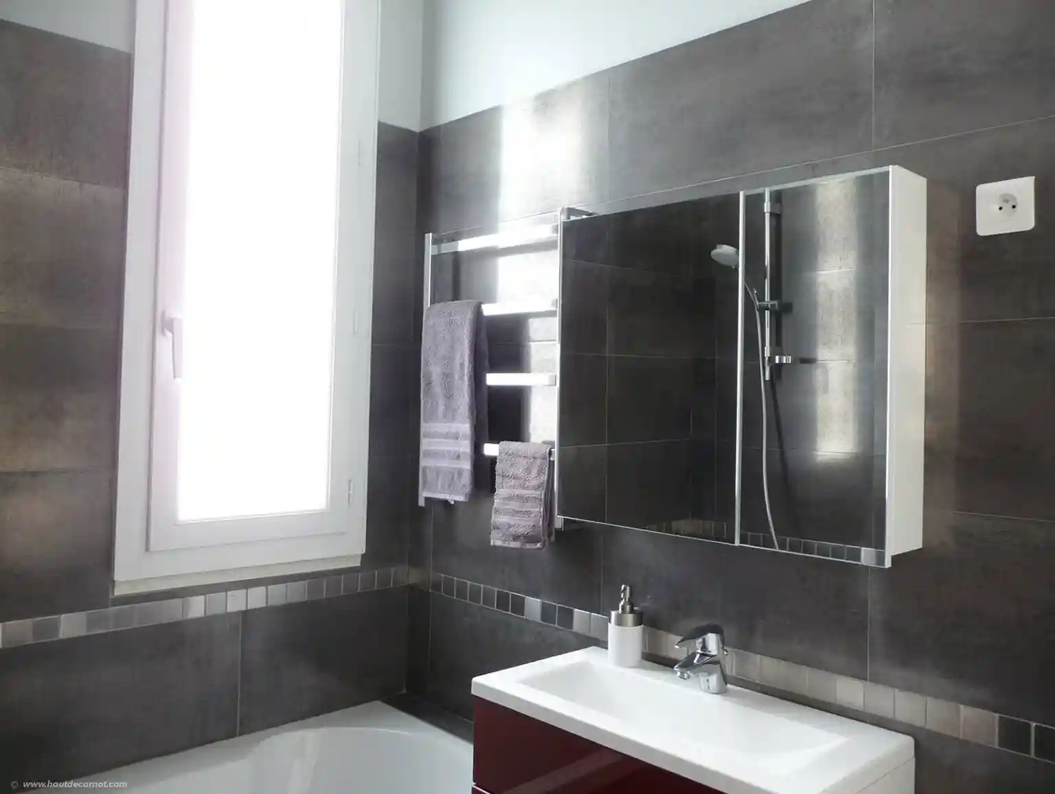 View of the bathroom with a large window, bathtub, shower, lavatory, cabinet with mirror 