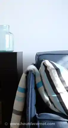Closeup on couch in the living room with cushions and wollen plaid for comfort